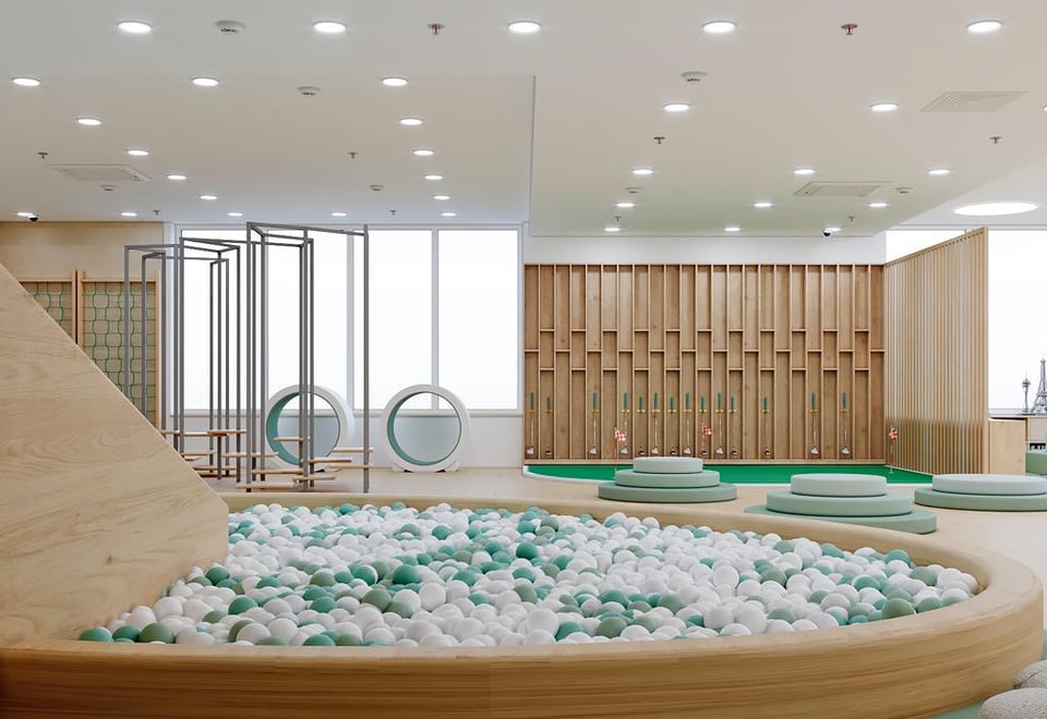 Ball pit with a timber slide, climbing frame and mini golf lane along the back wall