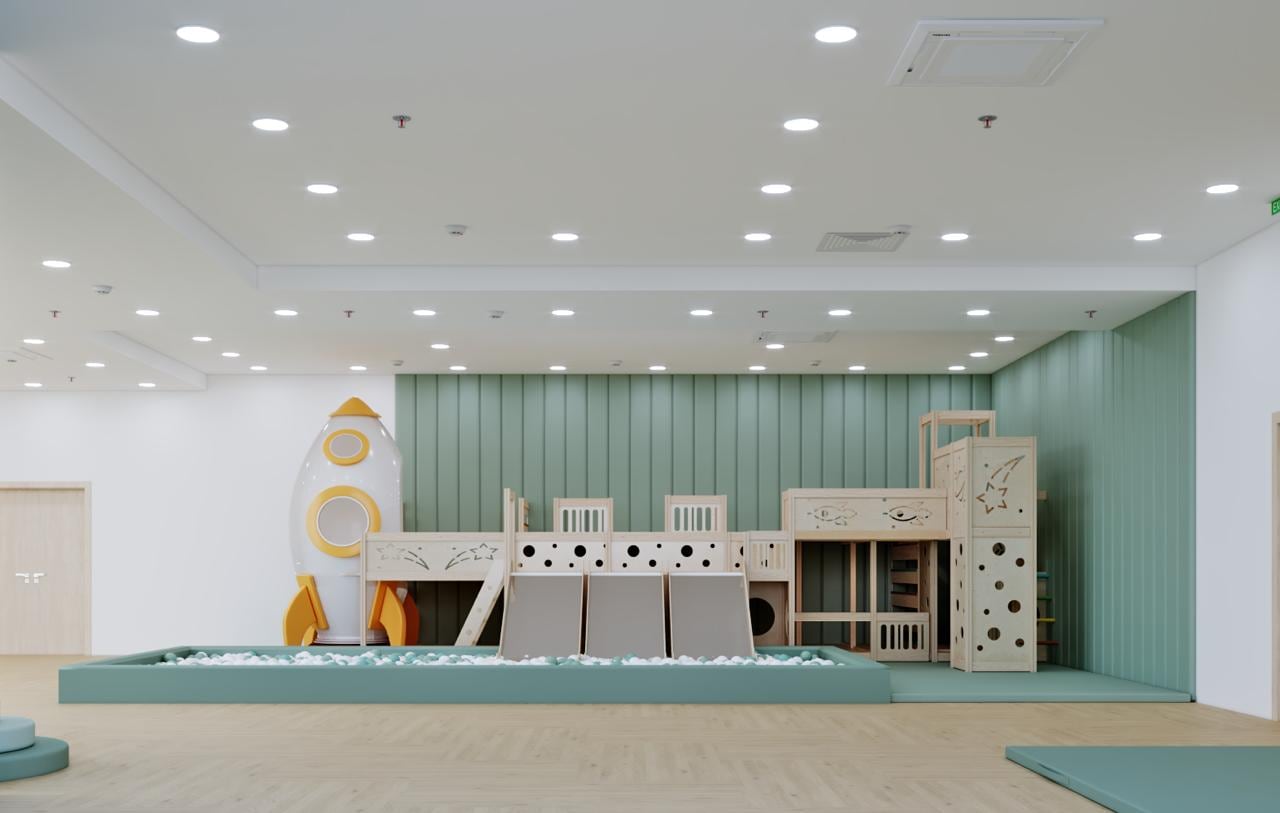 Rocket-ship play structure with slide and ball pit against a sage green panelled wall