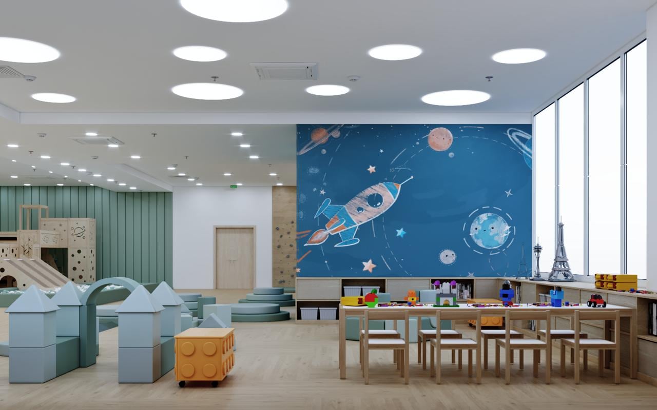 Space-themed activity room with a hand-painted rocket mural, modular play blocks and a long low activity table
