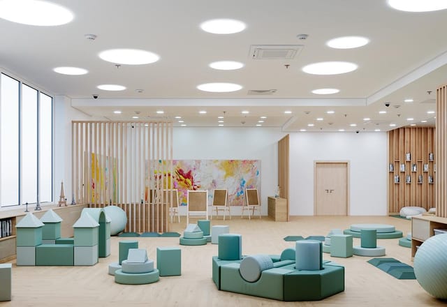 Play area of the children's educational centre by Anna Arsentyeva in Moscow: sage and mint foam play blocks, slatted timber screens, book display wall