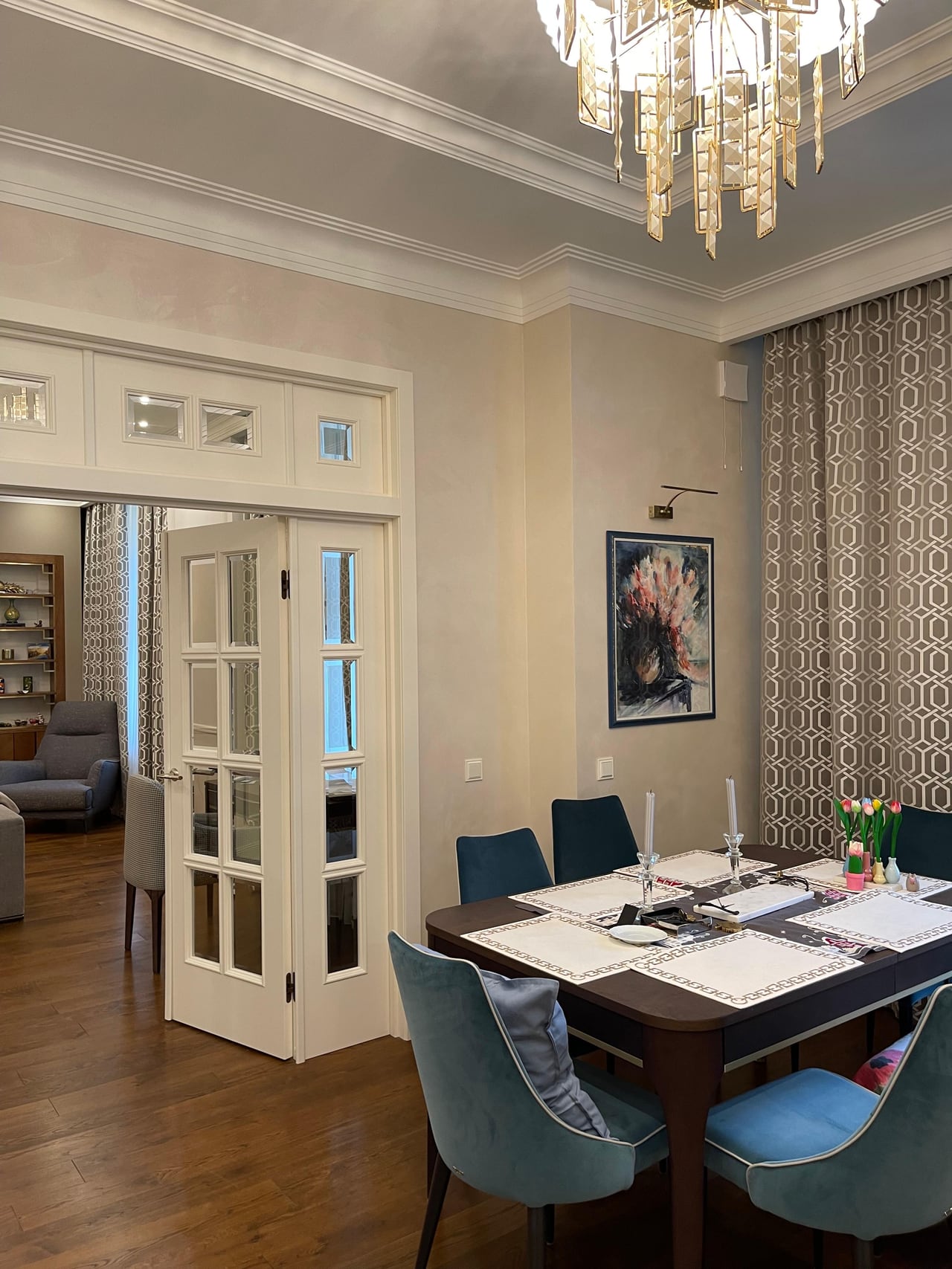Dining room with a folding glazed door to the living room, teal velvet chairs and a watercolour still life on the wall